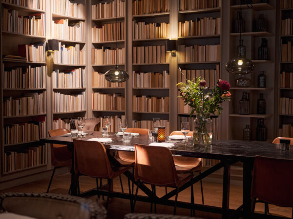 Intieme dinersetting met bruinleren stoelen, gedekte tafel en bloemen in een sfeervolle bibliotheekomgeving - Jazz and Wine Concert Events